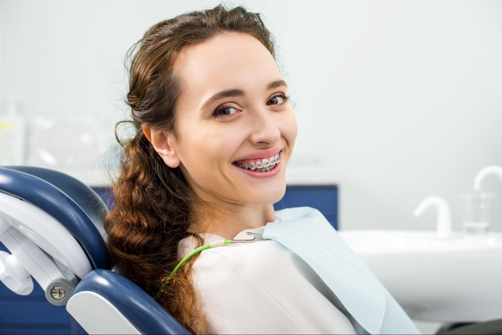 Smiling young woman with braces in dental chair at Oasis Orthodontics, emphasizing personalized orthodontic care in Gilbert, AZ.